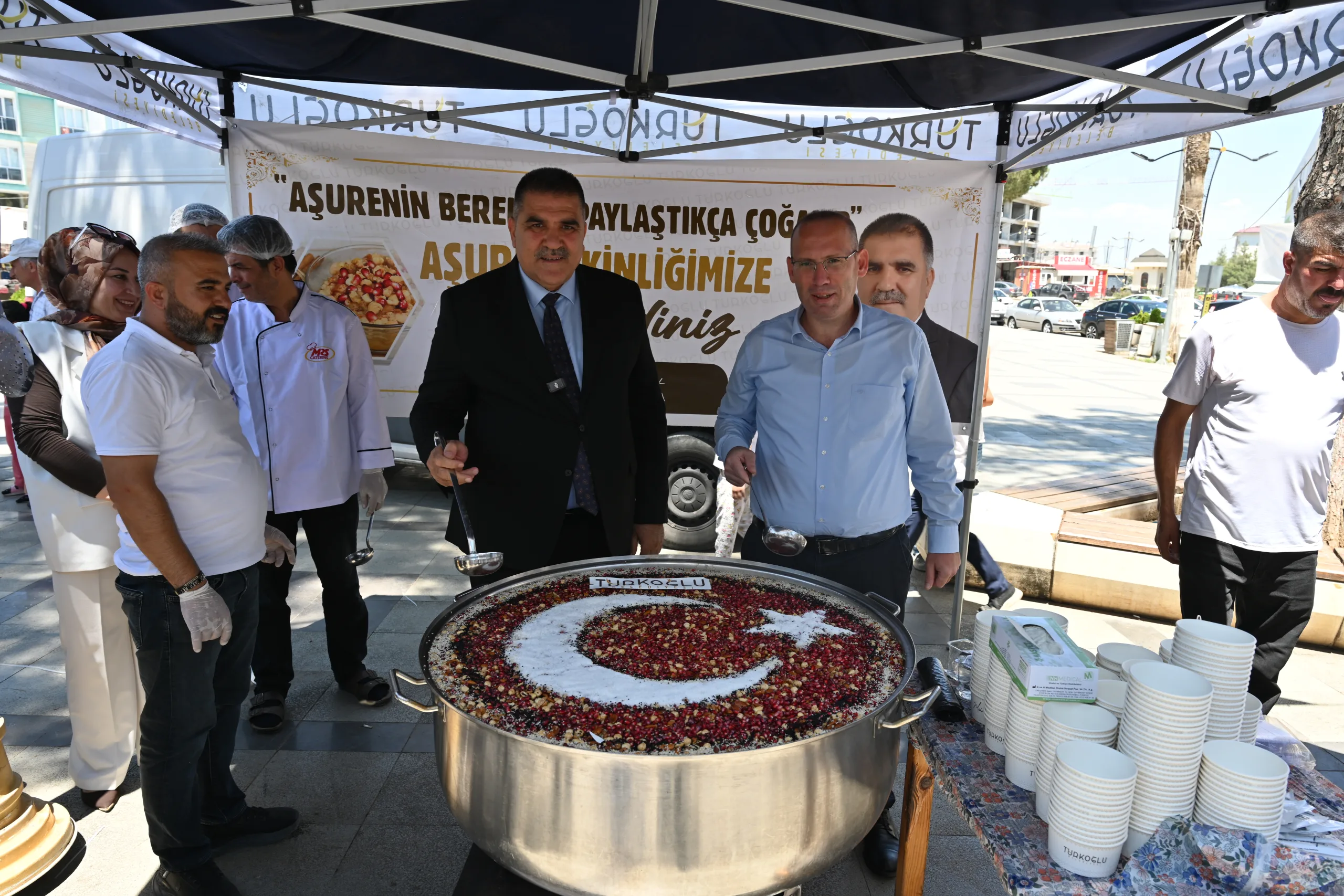 Aşure’nin bereketi Türkoğlu Millet Meydanında vatandaşlara sunuldu. Hemşerileriyle aşure sofrasında